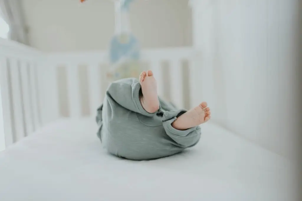 Cute baby feet in pajamas on a soft white crib. Perfect for children's room decor.